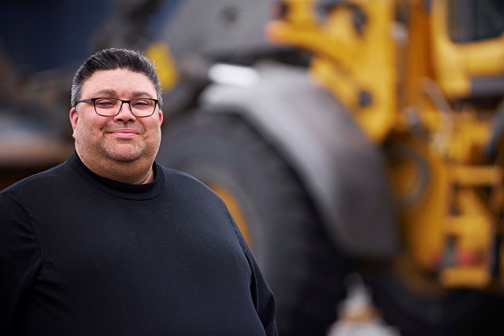 Karl Hoffman står framför en grävmaskin.