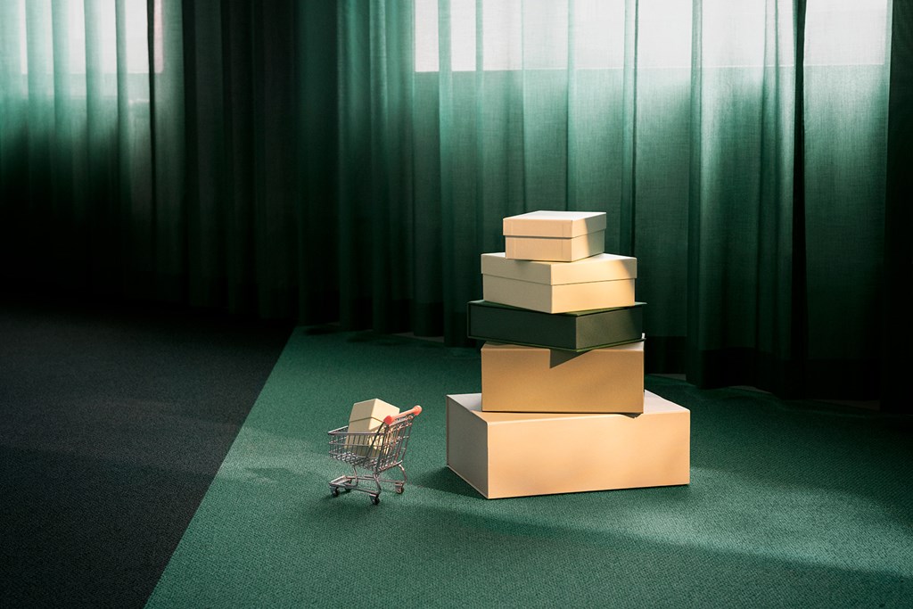 Stacked boxes and a small shopping cart on a green carpet in soft light