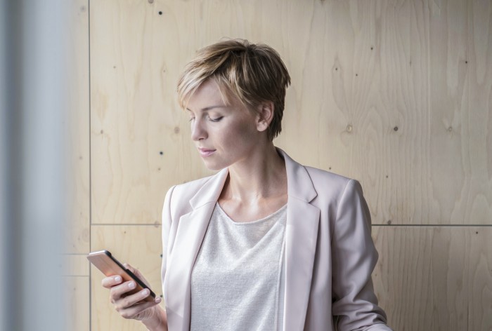 Business woman managing payments on mobile phone