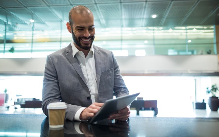 A smiling employee working on an tablet with a coffee